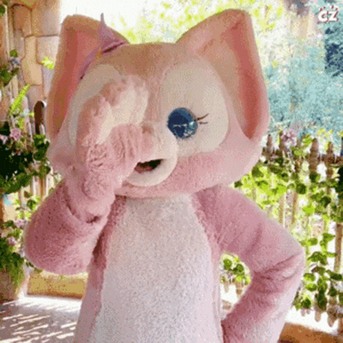 a stuffed animal in a pink and white cat costume covering one eye with its paw