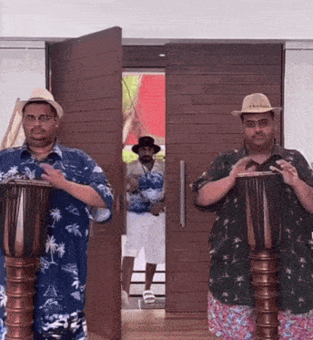 two men wearing hawaiian shirts and hats are playing drums in front of a door