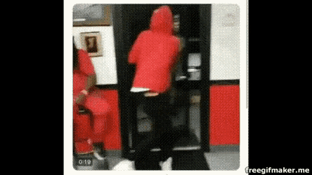 a person in a red hoodie is standing in front of a door .