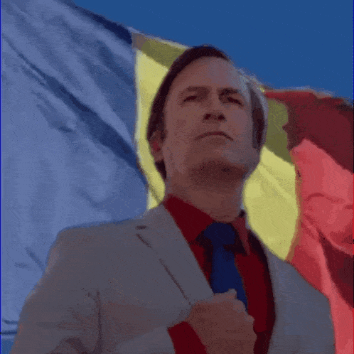 a man in a suit and tie standing in front of a flag