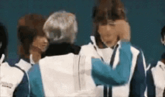 a group of people are standing next to each other and one of them is hugging another person .