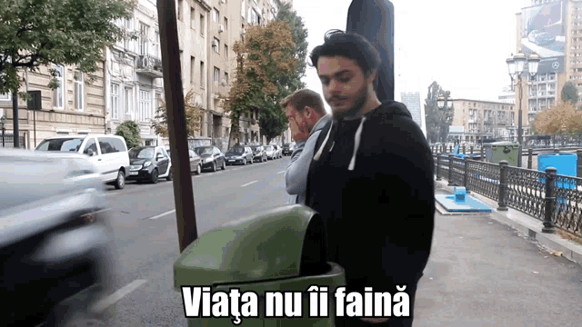 a man standing next to a trash can that says " viata nu ii faina " on it