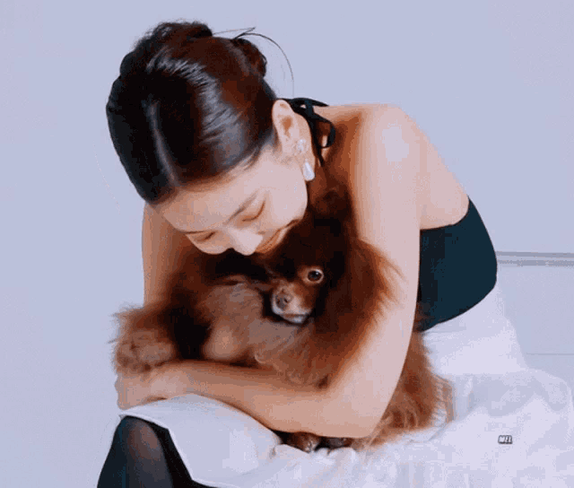 a woman in a black top and white skirt is holding a brown dog
