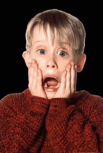 a young boy in a red sweater looks surprised with his mouth open