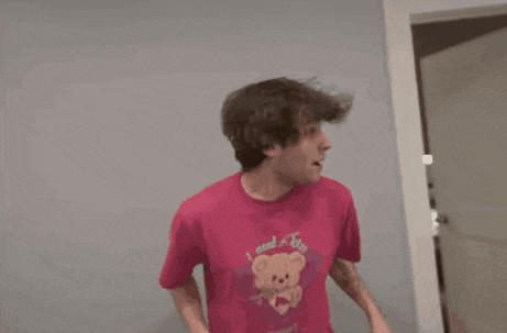 a man in a brown jacket is dancing in front of a refrigerator in a kitchen .