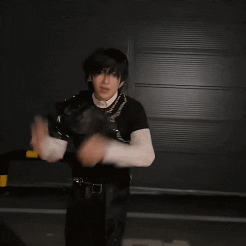 a man in a black and white outfit is dancing in front of a wall