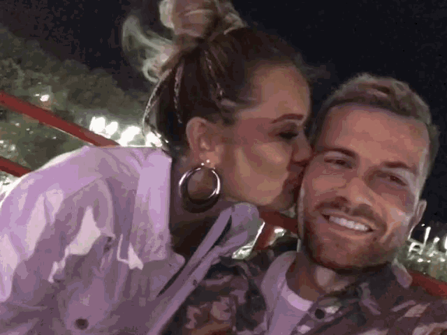 a woman kisses a man on the cheek while they pose for a picture