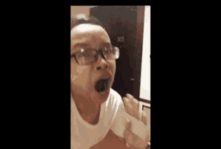 a person wearing glasses is making a funny face while holding a cell phone .