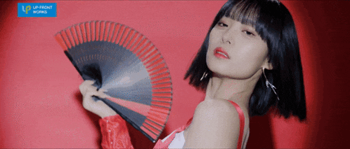a woman is holding a fan in front of a red background that says up front works