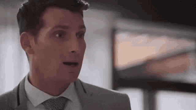 a man in a suit and tie is looking surprised .