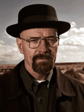 a man wearing a hat and glasses looks at the camera
