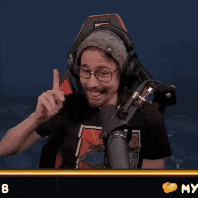 a man wearing headphones and glasses is sitting in front of a microphone with the number 8 below him