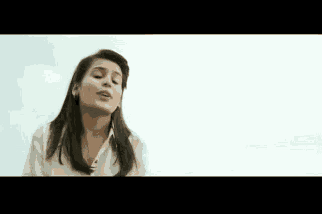 a woman in a white shirt is singing into a microphone