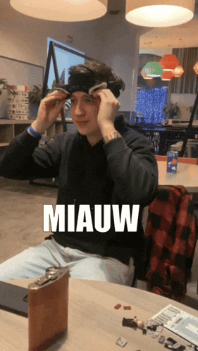a man is sitting at a table with the word miauw on the bottom
