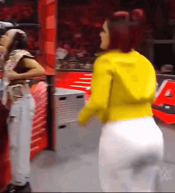 a woman in a yellow jacket and white pants is standing in front of a sign that says a .