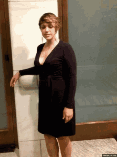 a woman in a black dress stands in front of a glass door
