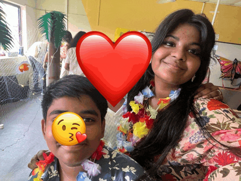 a girl and a boy are posing for a picture with a heart behind them