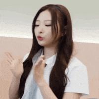 a woman with long brown hair is wearing a white shirt and a headband while waving her hands .