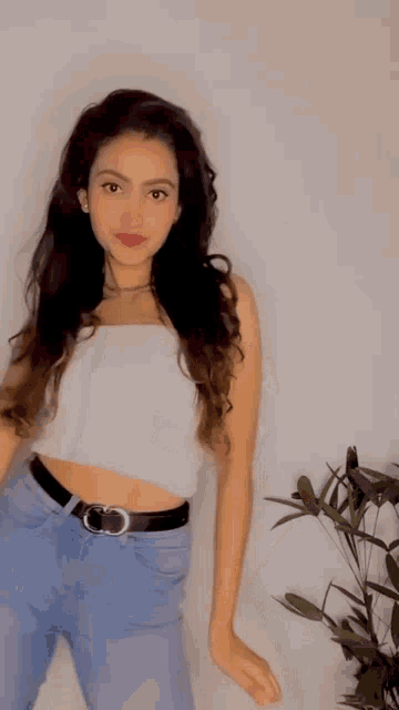 a woman in a white crop top and blue jeans