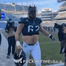 a football player wearing a batman mask and a crop top is walking off the field .