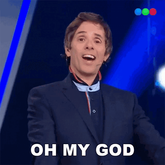 a man in a suit says oh my god in front of a microphone