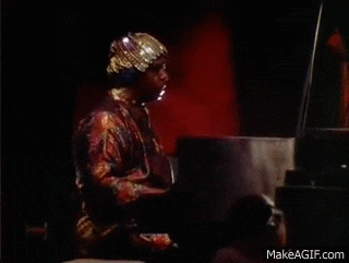 a man is playing a piano in a dark room with a red background .