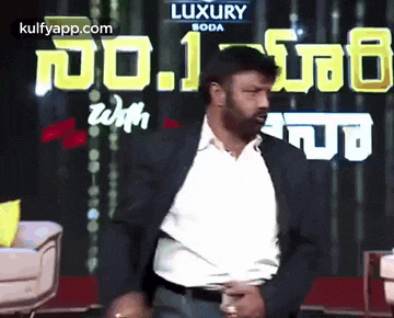 a man in a suit is dancing on a stage in front of a sign that says luxury soda .