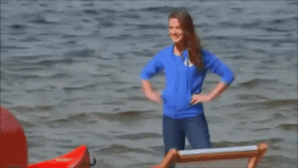 a woman in a blue sweater is standing in the water