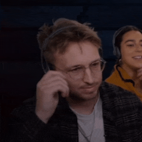 a man wearing headphones holds a pair of glasses to his mouth