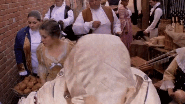 a group of people dressed in historical clothing are gathered in a room