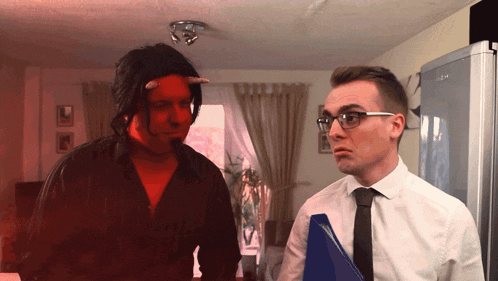 a man wearing glasses and a tie stands next to a man with horns