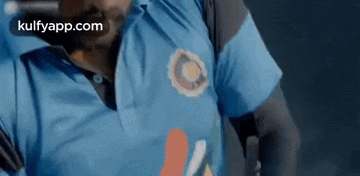 a close up of a man wearing a blue shirt with a logo on it .