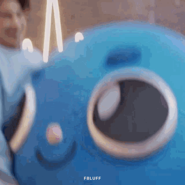 a blurry picture of a person holding a blue stuffed animal with the words f8luff on the bottom