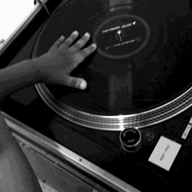 a black and white photo of a person touching a record
