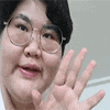 a woman wearing glasses and a white shirt is waving her hand .