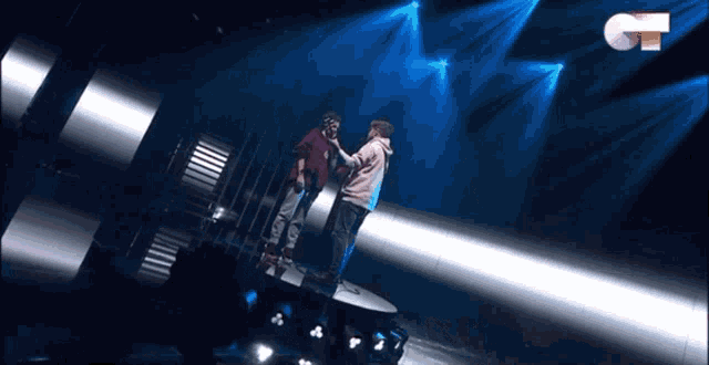 two men are standing on a stage with a ct logo in the background