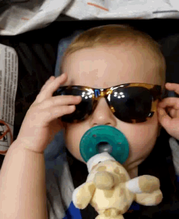 a baby wearing sunglasses and holding a pacifier