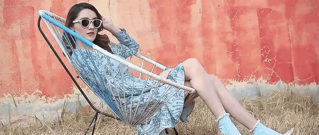 a woman in a blue dress is sitting in a chair with her legs crossed .