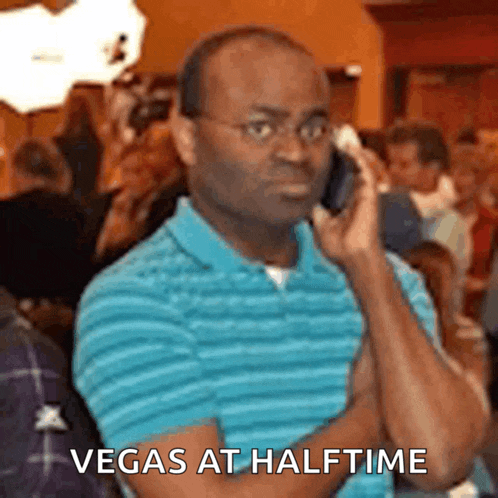 a man in a blue shirt is talking on a cell phone with the words vegas at halftime below him