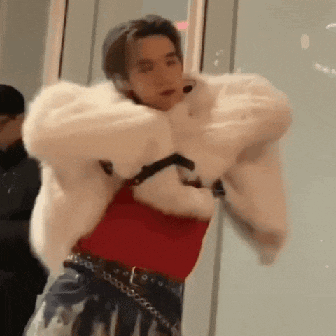 a man wearing a white fur coat and a red shirt is dancing .