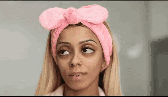 a woman wearing a pink headband is looking at the camera .