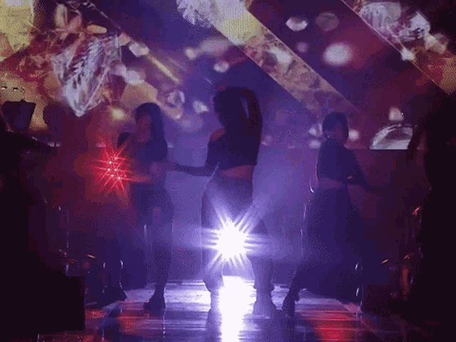 a group of women are dancing on a stage in front of a large screen