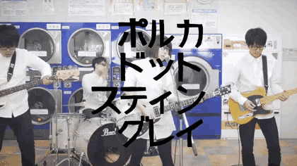 a group of people playing guitars and drums in front of a laundromat machine
