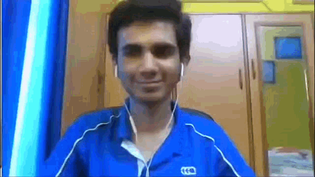 a man in a blue shirt is wearing headphones and smiling .