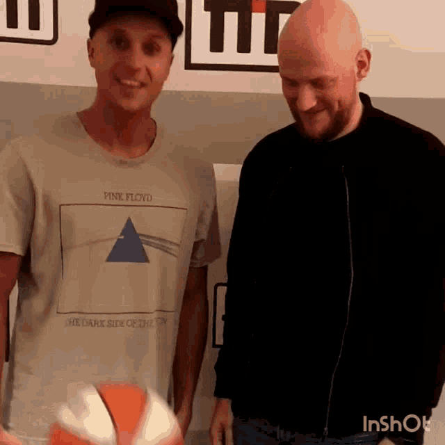 a man wearing a pink floyd shirt holds a basketball