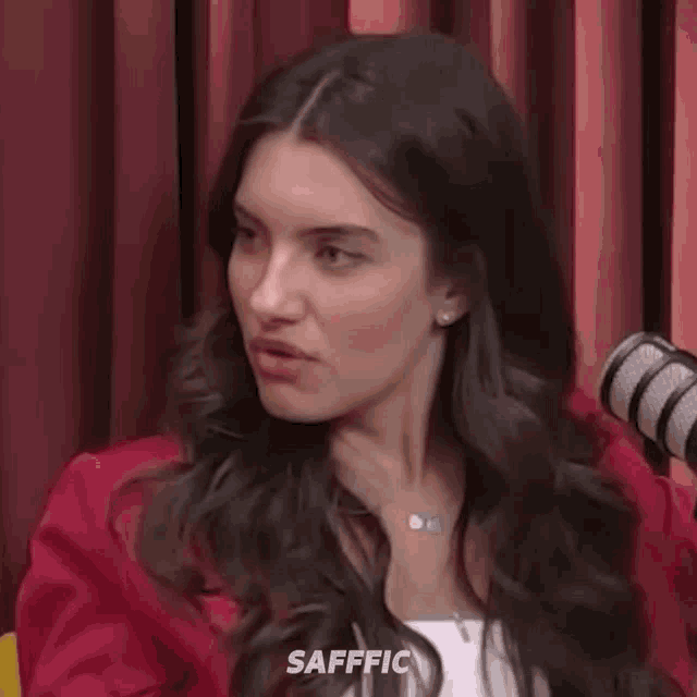 a woman in a red jacket is making a surprised face with her mouth open .
