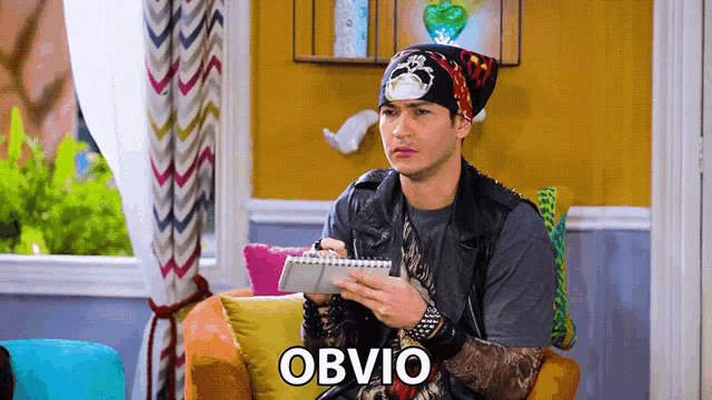 a man with a bandana on his head is writing in a notebook and the word obvio is on the bottom right