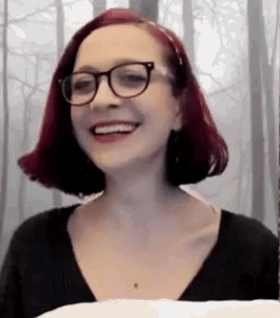 a woman with red hair is wearing glasses and smiling