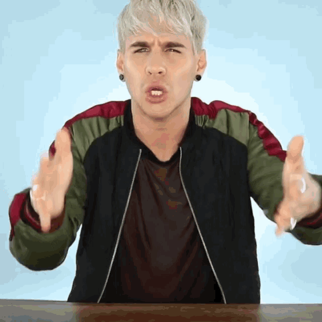 a man with blonde hair is making a funny face while sitting at a table