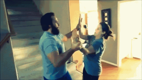 a man and woman are giving each other a high five in a living room .